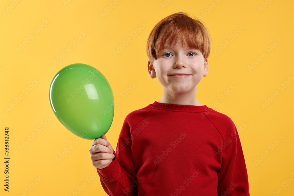 Boy with green balloon on orange background Boy with green balloon on orange background