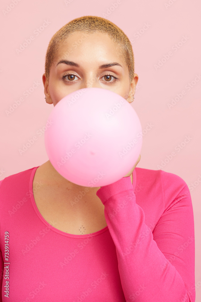 Young blond woman blowing pink balloon Young blond woman blowing pink balloon