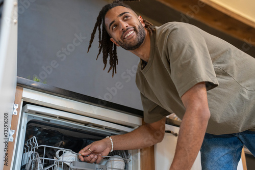 Man with dreads loading dishwasher photo