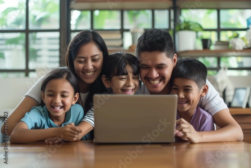 Happy Latin parents and two kids enjoying online entertainment with laptop, using Internet technology, application, communication, looking at computer screen together, laughing