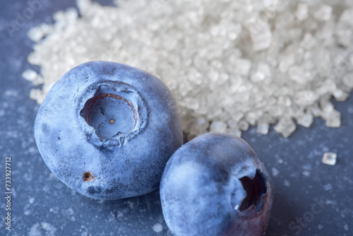 Macro shot of fresh raw blueberry. Clear sharp details and texture. Sugar is on background. Blueberries contain moderate amounts of natural sugar.