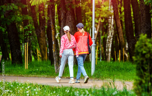 Two girlfriends walk along a path in the Park
