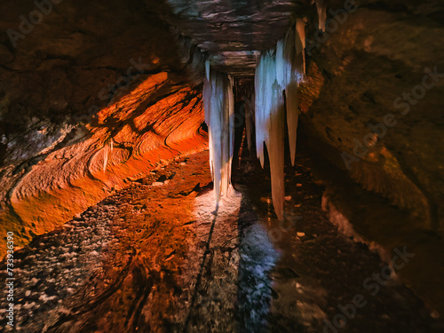 Fotografija The illuminated frozen waterfall of underground waters under the arches of a ma