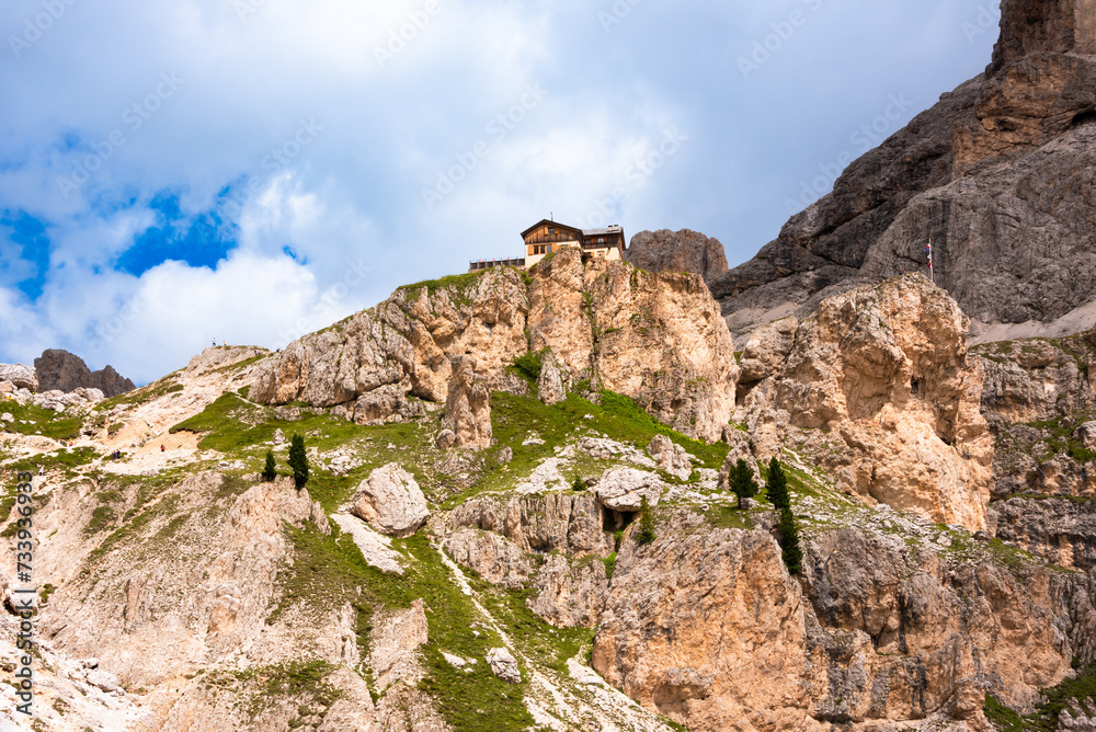 Dolomite alps and a house or mountain refuge on rock above