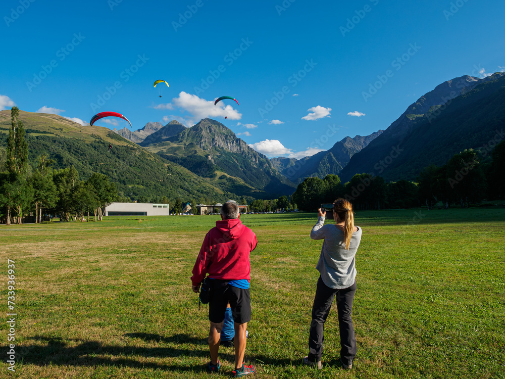 Naklejka premium An instructor from a paragliding school giving instructions to his students so that the approach and landing maneuver is safe, accompanied by the wife and son of one of the pilots