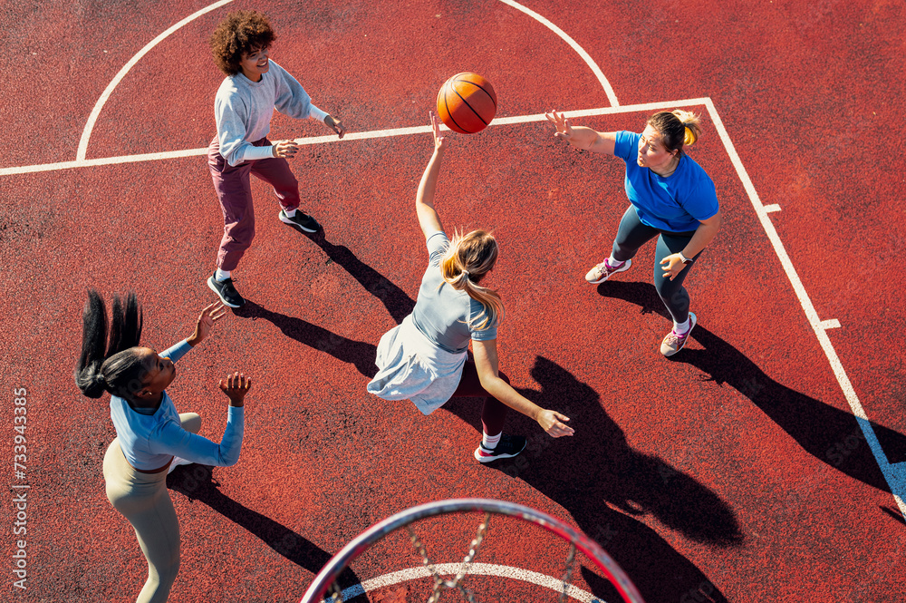 Top view of diverse group of young woman having fun playing basketball outdoors.