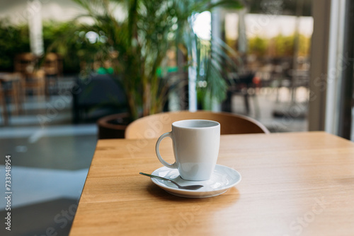 A Cup of freshly brewed black tea at a cafe blurred background. Coffee cup on table cafe shop Interior. Concept of easy breakfast. One white big ceramic cup. Top view. Mock up