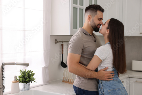 Affectionate couple hugging in kitchen. Space for text