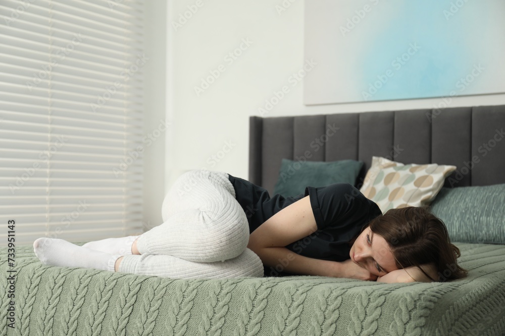 Sad young woman lying on bed at home Sad young woman lying on bed at home