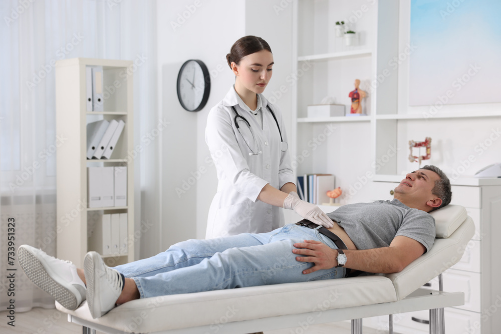 Fototapeta premium Gastroenterologist examining patient with stomach pain on couch in clinic