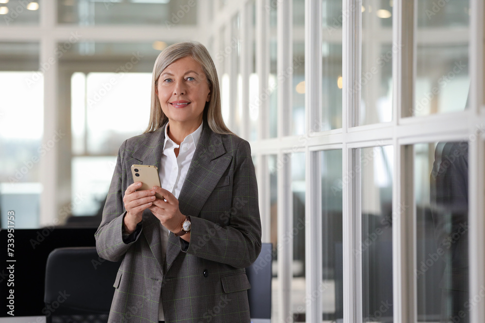 Smiling woman with smartphone in office, space for text. Lawyer, businesswoman, accountant or manager Smiling woman with smartphone in office, space for text. Lawyer, businesswoman, accountant or manager