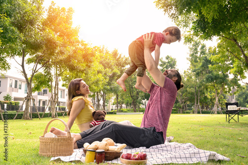 happy family spending time on summer day. Father lifted son into the air while picnicking in the park on a summer day.