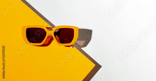 Minimal style composition made of trendy sunglasses on orange and white sunlit background