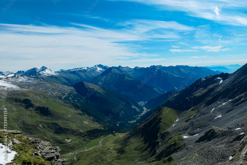 Panoramic view of majestic cloud covered mountain peaks of High Tauern, Carinthia Salzburg, Austria. Idyllic hiking trail in Goldberg group in wilderness of Austrian Alps. Tranquil mystical atmosphere