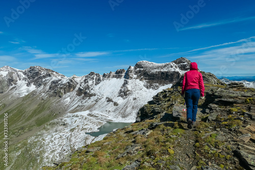 Hiker woman with scenic view of majestic mountain peaks of High Tauern seen from Feldseekopf, Carinthia Salzburg, Austria. Idyllic hiking trail in Goldberg group in remote Austrian Alps. Wanderlust