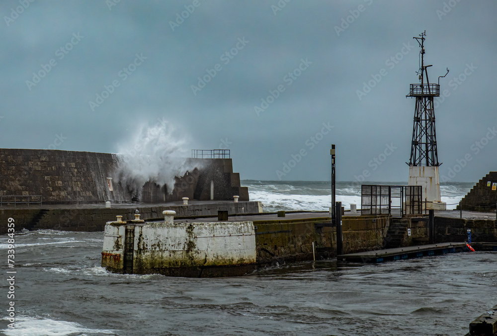 Storm at sea with waves crashing over harbour wall