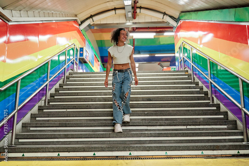 full view of a gay man walking down the stairs of a subway station with the gay pride flag on the walls. photo