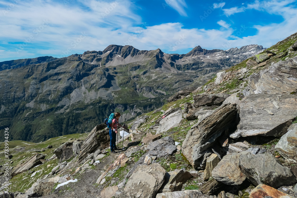 Hiker woman and unique rock formations with scenic view of mountain peak Weissseekopf in wild High Tauern, Carinthia Salzburg, Austria. Idyllic hiking trail Goldberg group. Wilderness of Austrian Alps Hiker woman and unique rock formations with scenic view of mountain peak Weissseekopf in wild High Tauern, Carinthia Salzburg, Austria. Idyllic hiking trail Goldberg group. Wilderness of Austrian Alps