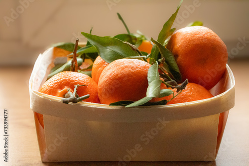 tangerines with green leaves in a wooden box