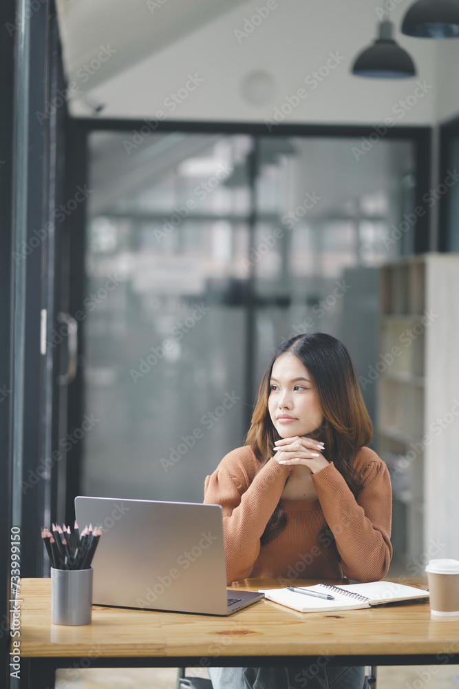 Fototapeta premium Beautiful young concentrated business woman wearing shirt using laptop while standing in modern workspace