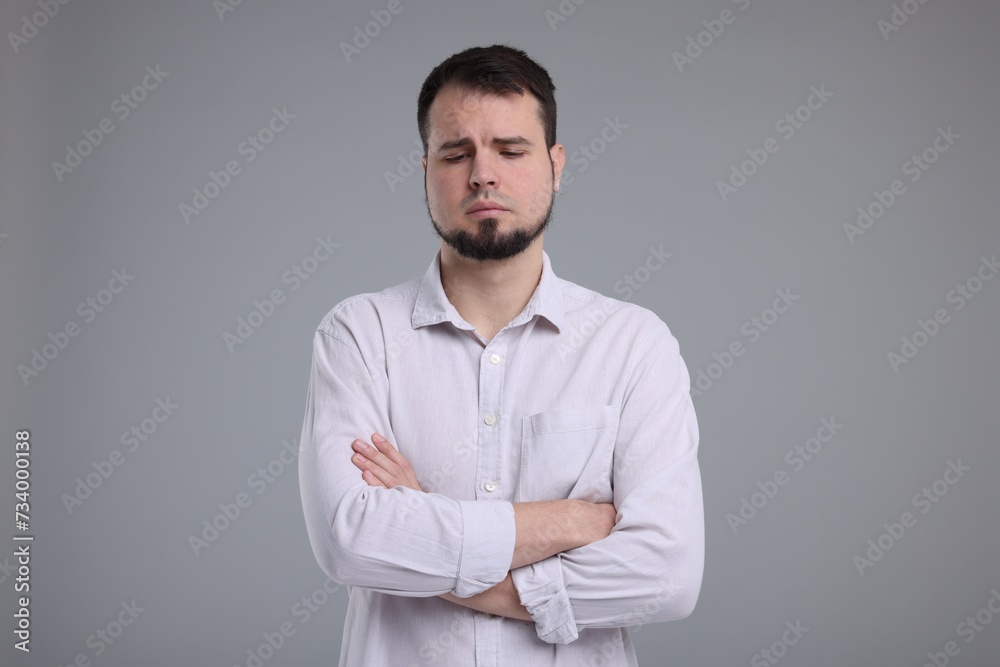 Portrait of sad man with crossed arms on grey background Portrait of sad man with crossed arms on grey background
