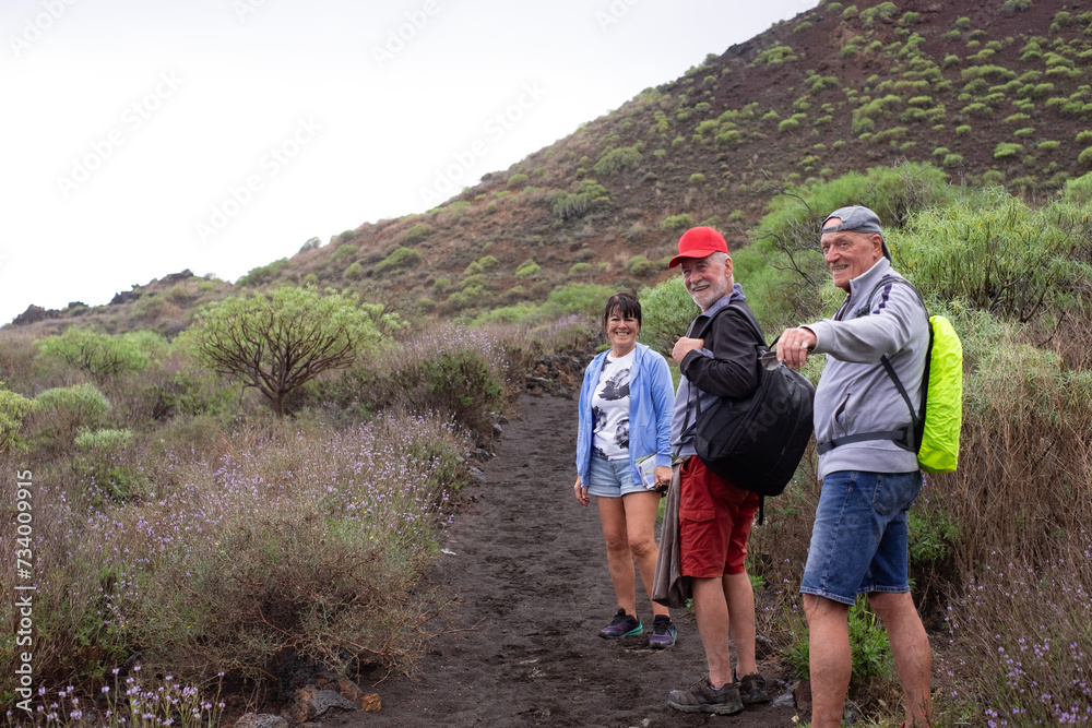 Smiling group of caucasian friends walking in the nature of Malpais de Guimar at Tenerife island with backpack on shoulders Smiling group of caucasian friends walking in the nature of Malpais de Guimar at Tenerife island with backpack on shoulders