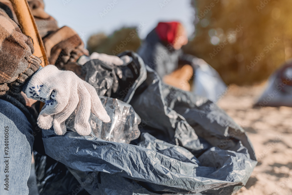 Close up shot of child in gloves collecting plastic bottles on the beach. Environmentalism, eco-system saving protection concept. Zero-waste way of living recycling