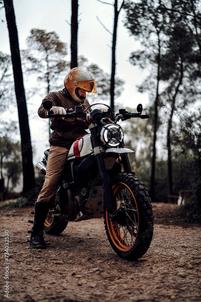 Fototapeta premium Hombre moreno con moto dentro de un bosque posando y montando por terreno silvestre