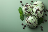 Mint chocolate chip ice cream scoops and mint leaves on a green background