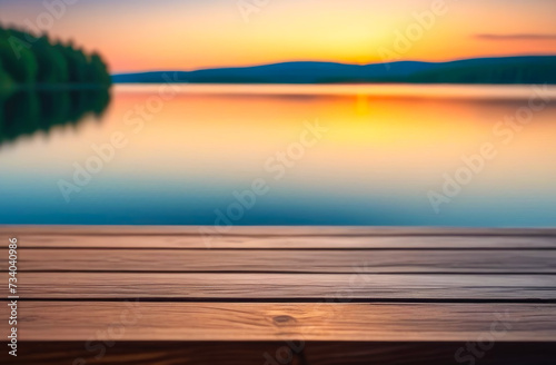 Empty wooden table with copy space for product presentation, against the backdrop of a summer lake and the setting sun. photo