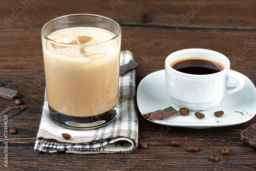 A cup of coffee and a glass of original Irish cream liqueur in a glass with ice.