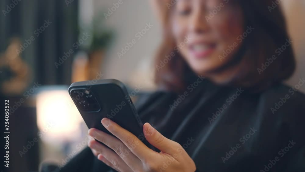 Closeup - happy asian woman client in beauty salon using social media on mobile phone while hairdresser giving beauty salon service and treatment Closeup - happy asian woman client in beauty salon using social media on mobile phone while hairdresser giving beauty salon service and treatment