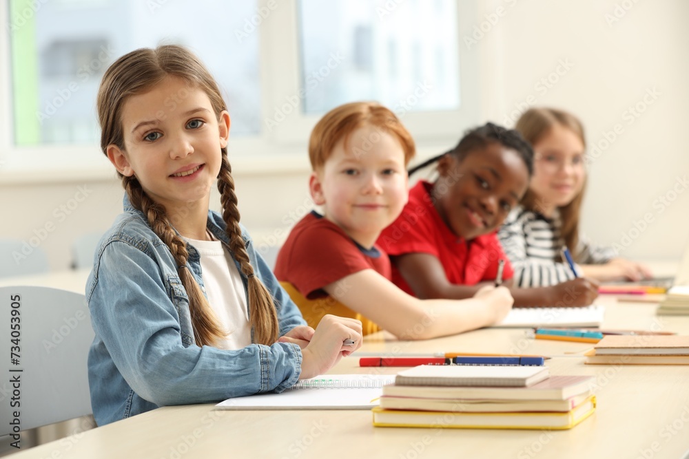 Smiling girl with her classmates studying in classroom at school Smiling girl with her classmates studying in classroom at school