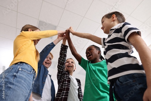 Happy children giving high five at school, low angle view