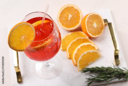 Glass of tasty Aperol spritz cocktail with orange slices and rosemary on white table, above view