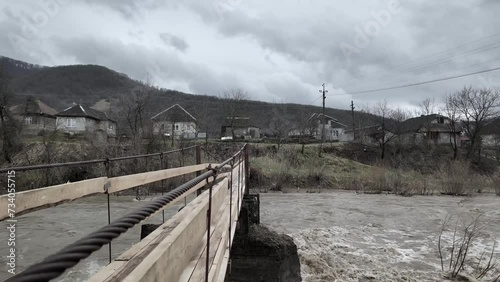 Ukraine, Carpathians, Transcarpathia, severe flooding in the mountains in winter after rains, a mass of water flows into the valleys, a menacing sight from a hanging rope bridge photo