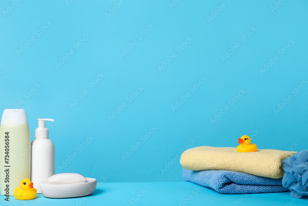 Baby cosmetic products, bath ducks, sponge and towels on light blue background. Space for text - obrazy, fototapety, plakaty 