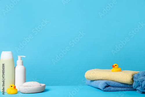 Baby cosmetic products, bath ducks, sponge and towels on light blue background. Space for text © New Africa