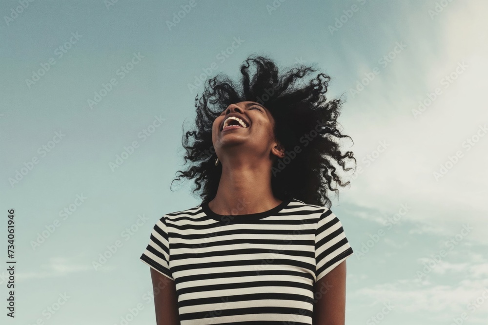 Joyful woman with curly hair laughing against a clear sky, epitomizing freedom and positivity in a casual setting Joyful woman with curly hair laughing against a clear sky, epitomizing freedom and positivity in a casual setting