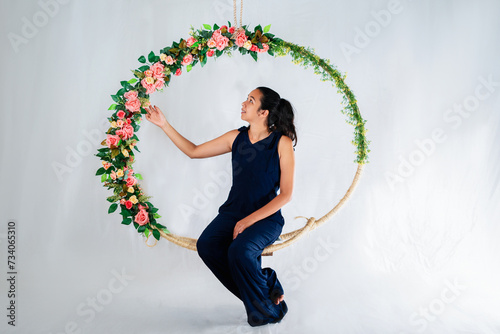 Mulher sentada em arco de flores para ensaio fotográfico em estúdio photo