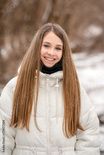 A young girl in a white warm jacket in winter outdoors