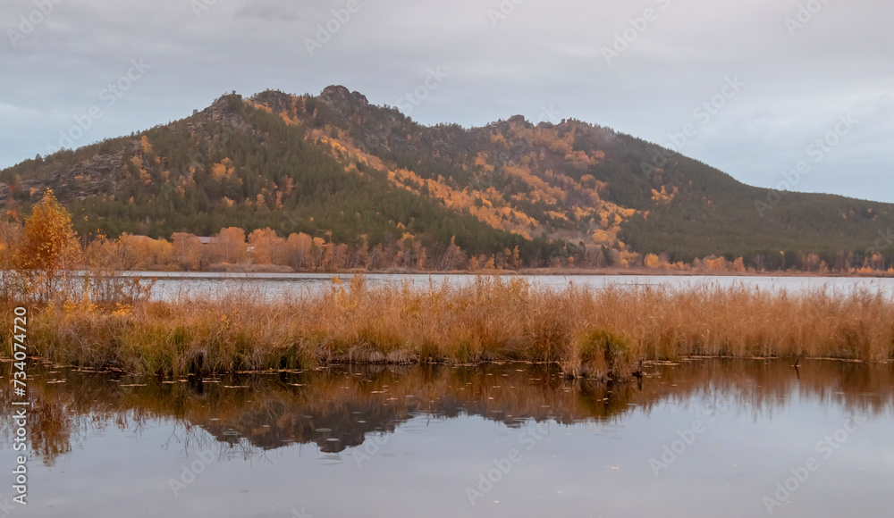 calm lake with grass and mountain in fog in the background
