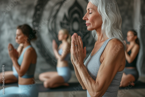 A group of senior women practices meditation in a yoga class.