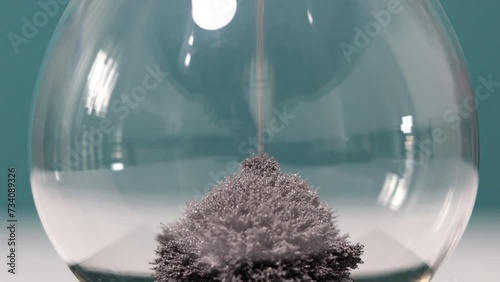 Detail of metal dust falling on the bottom of hourglass magnet. Concept of time passing.