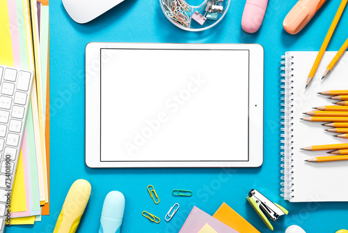 Modern tablet and stationery on light blue background, flat lay. Space for text