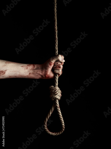 Human hand holding noose over black background 