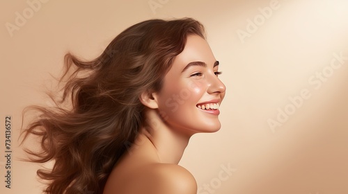 Portrait of smiling girl enjoying beauty treatment on beige background. Beautiful natural woman looking at copy space, spa and wellness concept. Carefree laughing woman with bare shoulders isolated.