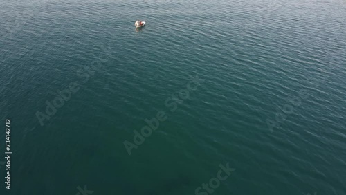 drone: vista su piccola barca bianca con pescatore su mare azzurro. photo
