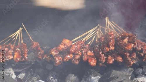 Chicken satay on fiery charcoal grilling by people in Indonesia photo