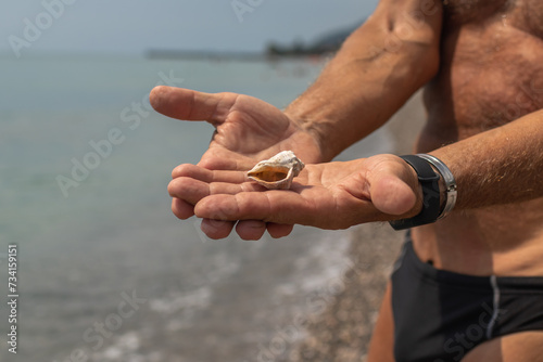 Sea shells in man's hands. Sea shore and waves. Vacation concept
